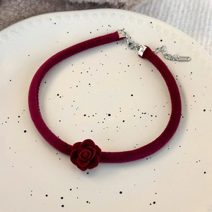 Détail d'un ras-de-cou en velours rouge avec rose et fermoir sur une assiette en céramique