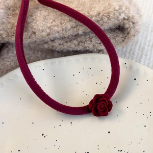 Vue rapprochée du ras-de-cou fleur en velours bordeaux sur une assiette chic