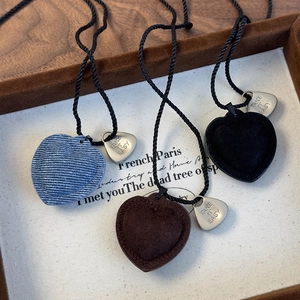 Detalle de colgantes de corazón vintage en denim y ante con placas Take It Easy de plata
