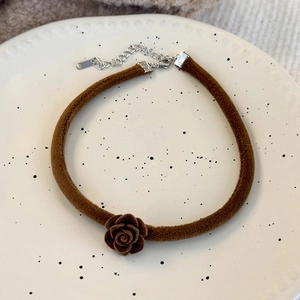 Gros plan d'un choker en velours marron avec rose en relief et fermoir mousqueton en métal