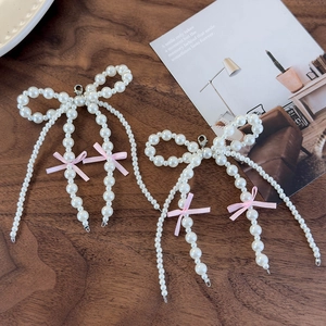 Detail of pink bow and pearl shoe charms with cascading tassels and silver clasps