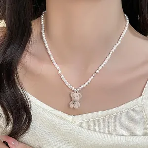 Gros plan du collier de perles avec un petit pendentif ours en velours brun sur mannequin