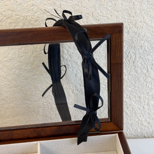 Detail of elegant black satin headband with three bows on a vintage wooden jewelry box