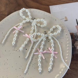 Detailed view of handmade pearl bow shoe charms with pink silk ribbon and beaded tassels
