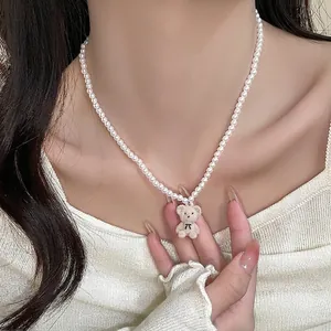 Collier de perles avec pendentif ours en velours mignon porté par un mannequin