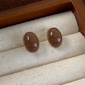 Detailed macro view of oval brown enamel stud earrings in a vintage gold frame