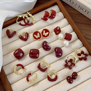 Detail view of red enamel butterfly heart earrings with gold plating on velvet tray