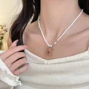 Détail d'un pendentif ours en velours brun sur un collier de perles pour femme