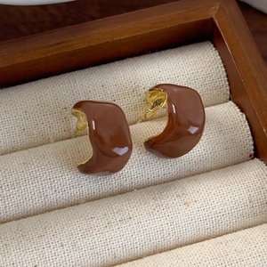 Close-up of vintage brown enamel C-shape stud earrings in a wooden jewelry box
