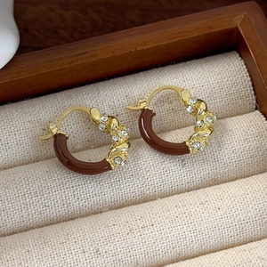 Macro view of gold hoop earrings with brown enamel and sparkling white crystals