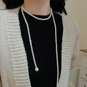 Detailed view of layered long pearl necklace on model with elegant minimalist design