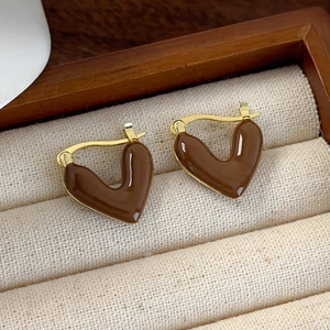 Close-up of vintage golden heart-shaped earrings with brown enamel on striped jewelry box