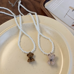Détail de pendentifs ours en peluche et de colliers de perles brillantes sur une assiette