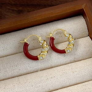 Detail van rode emaille en goudkleurige oorringen met kristallen op een doosje