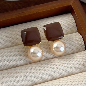 Macro shot of vintage style brown enamel square earrings with champagne pearl drops