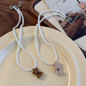 Colliers de perles élégants avec pendentifs d'ours en velours marron et beige sur une assiette