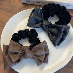 Set of black and brown double-layer leather bow scrunchies with velvet bands on ceramic plate