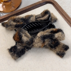 Detail of plush leopard print faux fur hair claw clip on a rustic wooden tray