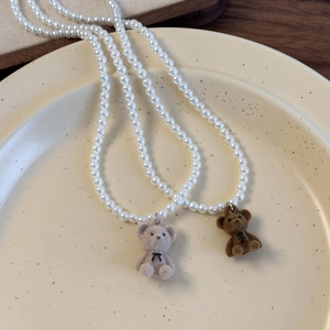 Gros plan détaillé des pendentifs ours en velours sur colliers de perles bicolores