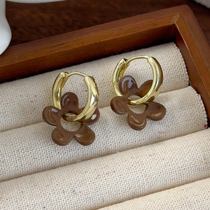 Brown flower enamel drop earrings in gold finish on a rustic wooden jewelry display