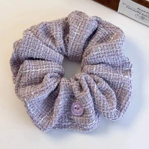 Detailed view of elegant purple tweed scrunchie with textured weave and decorative button