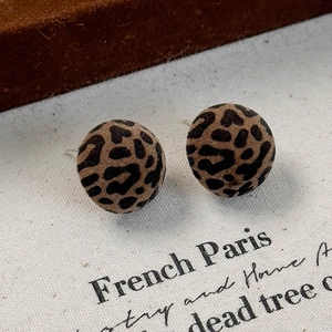 Detailed macro view of vintage leopard print flocked button earrings on white canvas