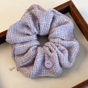 Detail of lavender tweed scrunchie featuring a purple button and soft woven texture