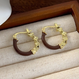 Macro detail of vintage gold and brown enamel hoop earrings in a wooden jewelry box