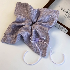 Close-up of purple tweed scrunchie with elegant button and ribbon bow details
