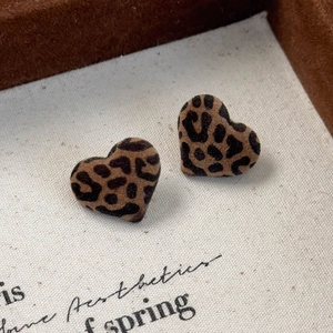 Macro shot of heart-shaped leopard print earrings with a soft flocked texture