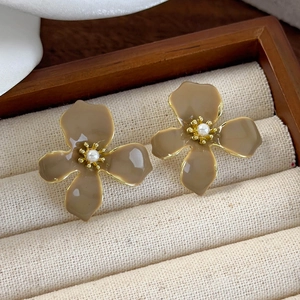 Macro shot of vintage floral stud earrings with mocha enamel petals and centered pearl