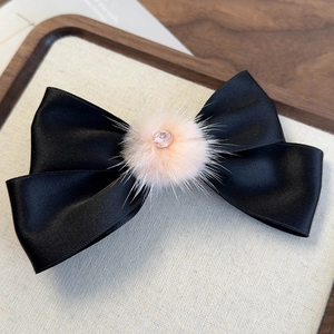 Dettaglio del fiocco in raso nero con pompon in ecopelliccia rosa e strass centrale