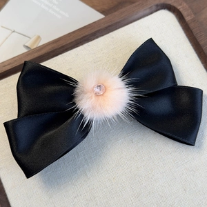 Dettaglio del fermaglio in raso nero con pompon rosa e centro in cristallo luccicante