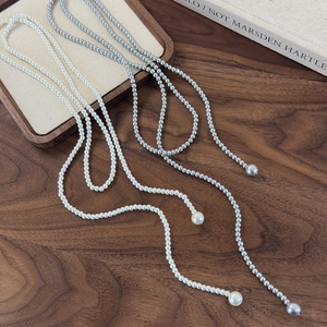 Detail of long layered pearl necklaces in white and grey with elegant drop pendants