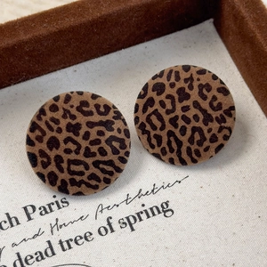 Close-up of vintage leopard print flocking round earrings on a soft beige jewelry stand