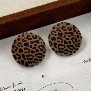 Macro detail of vintage leopard print flocking round stud earrings on a textured paper background