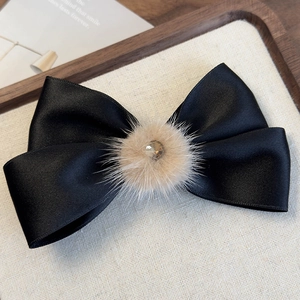 Dettaglio elegante fiocco in raso nero con pompon di peluche e centro di strass