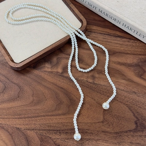Detailed view of long pearl necklace featuring white beads and elegant pendant drops