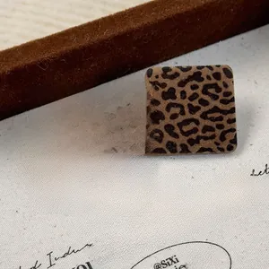 Close-up of square leopard print earrings with vintage flocked texture on art paper