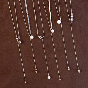 Detail of adjustable silver Y-necklace featuring pearls and metallic bead pendants