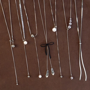 Detailed macro of silver long pearl necklaces with velvet bow and ballet shoe charms