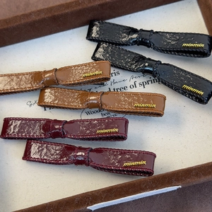 Three leather bow hair clips in black, burgundy and brown with elegant gold metal accents