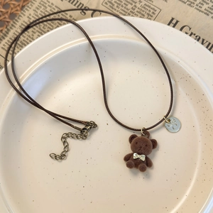Gros plan du pendentif ours brun floqué sur collier en corde de cire avec nœud doré