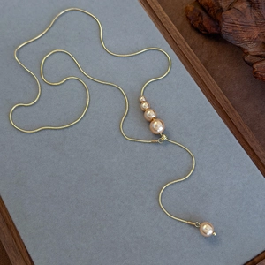 Detail of adjustable gold snake chain Y-necklace featuring elegant champagne pearls