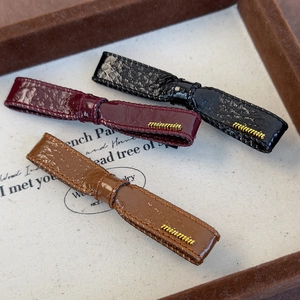 Three elegant bow hair clips in black, burgundy and brown leather with gold metal accents