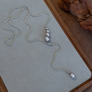 Macro detail of adjustable silver-tone Y-shaped long necklace with grey pearls on display