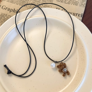 Détail du pendentif ours en peluche marron avec perle et strass sur cordon noir