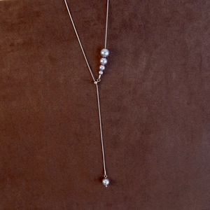Macro shot of silver Y-shape adjustable pearl necklace with gray gradient pearls