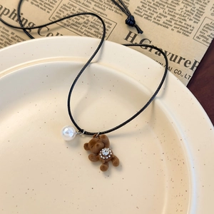 Détail du pendentif ours brun floqué avec perle et strass sur cordon noir
