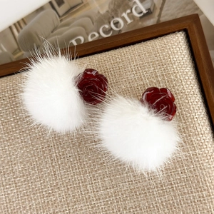 Detail view of red resin rose earrings with soft white fluffy pompom on linen texture